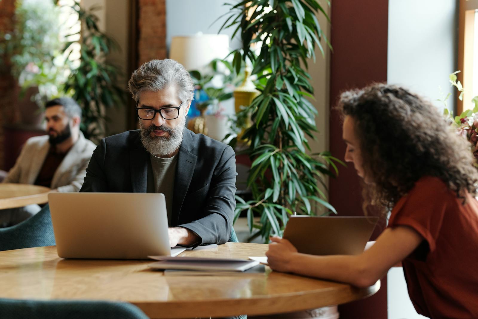 Two professionals working together on laptops in a modern coworking space