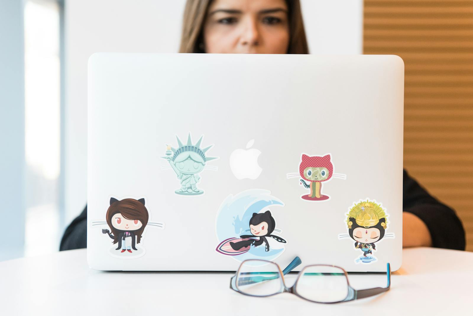 A woman at a laptop with GitHub stickers on the device