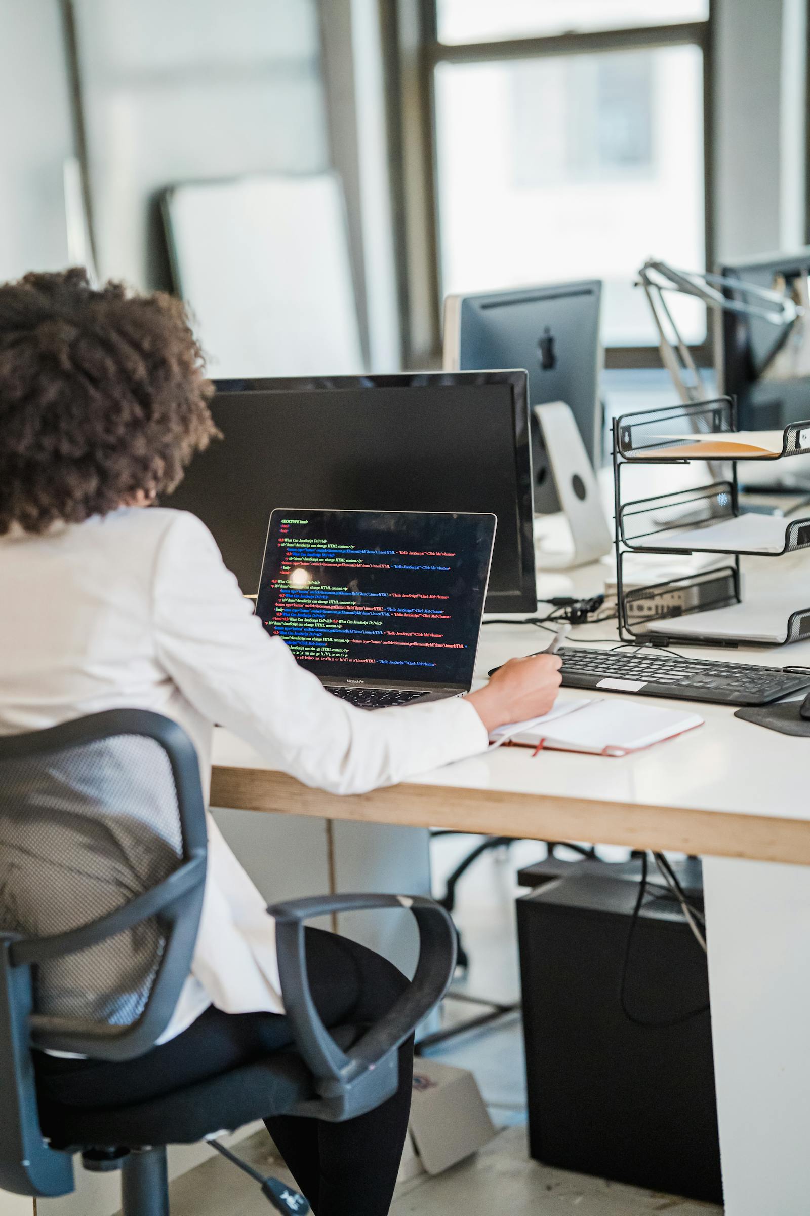 A businesswoman focused on coding at her desk in a modern office