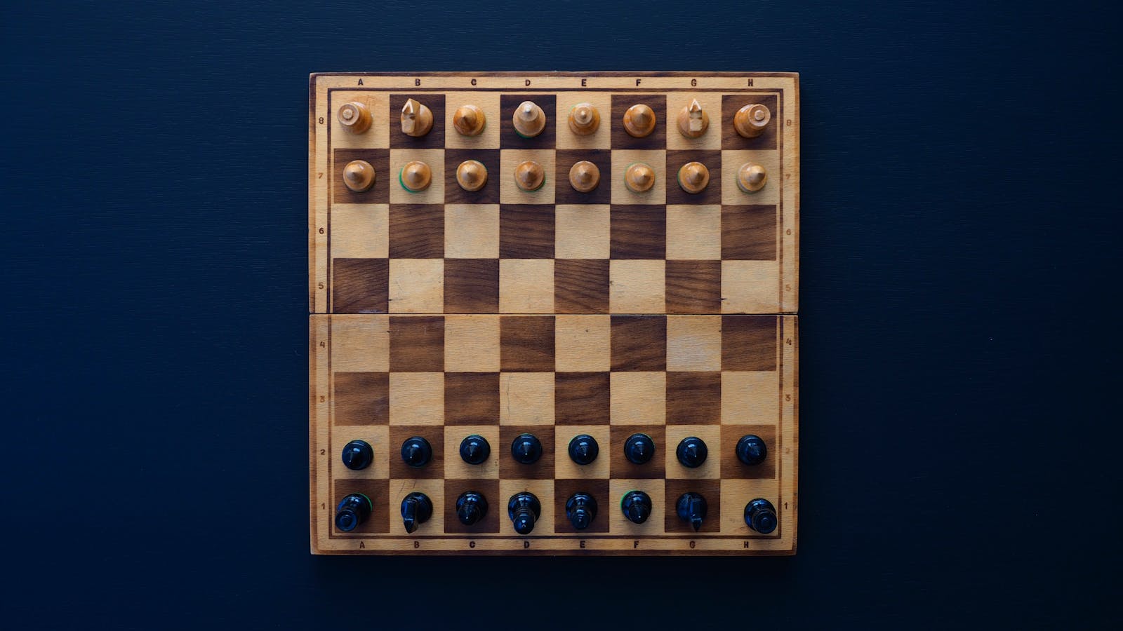 A wooden chess board with pieces in mid-game position