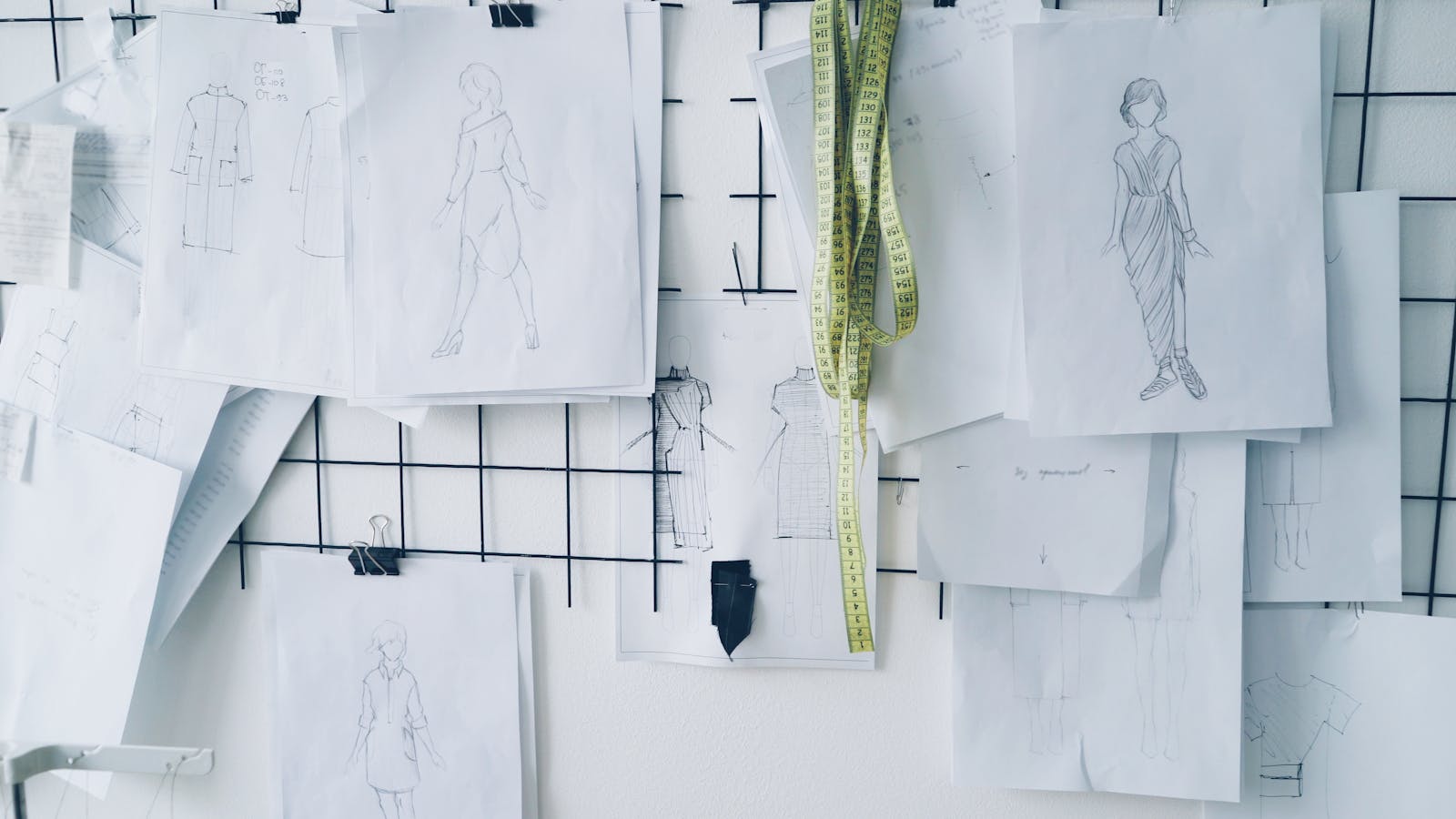 Fashion sketches with measuring tape on a designer's wall
