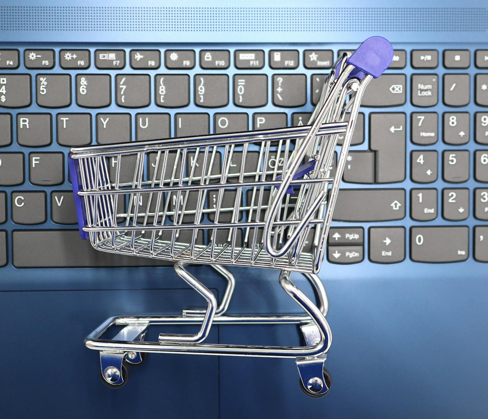 A miniature shopping cart on a laptop keyboard representing e-commerce