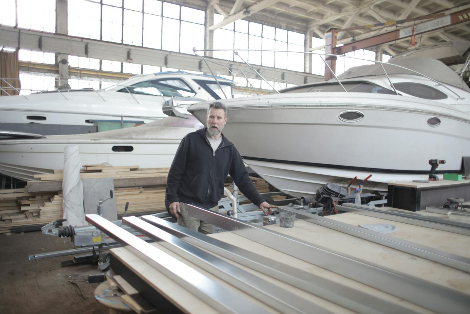 A craftsman working on metal components inside a yacht hangar