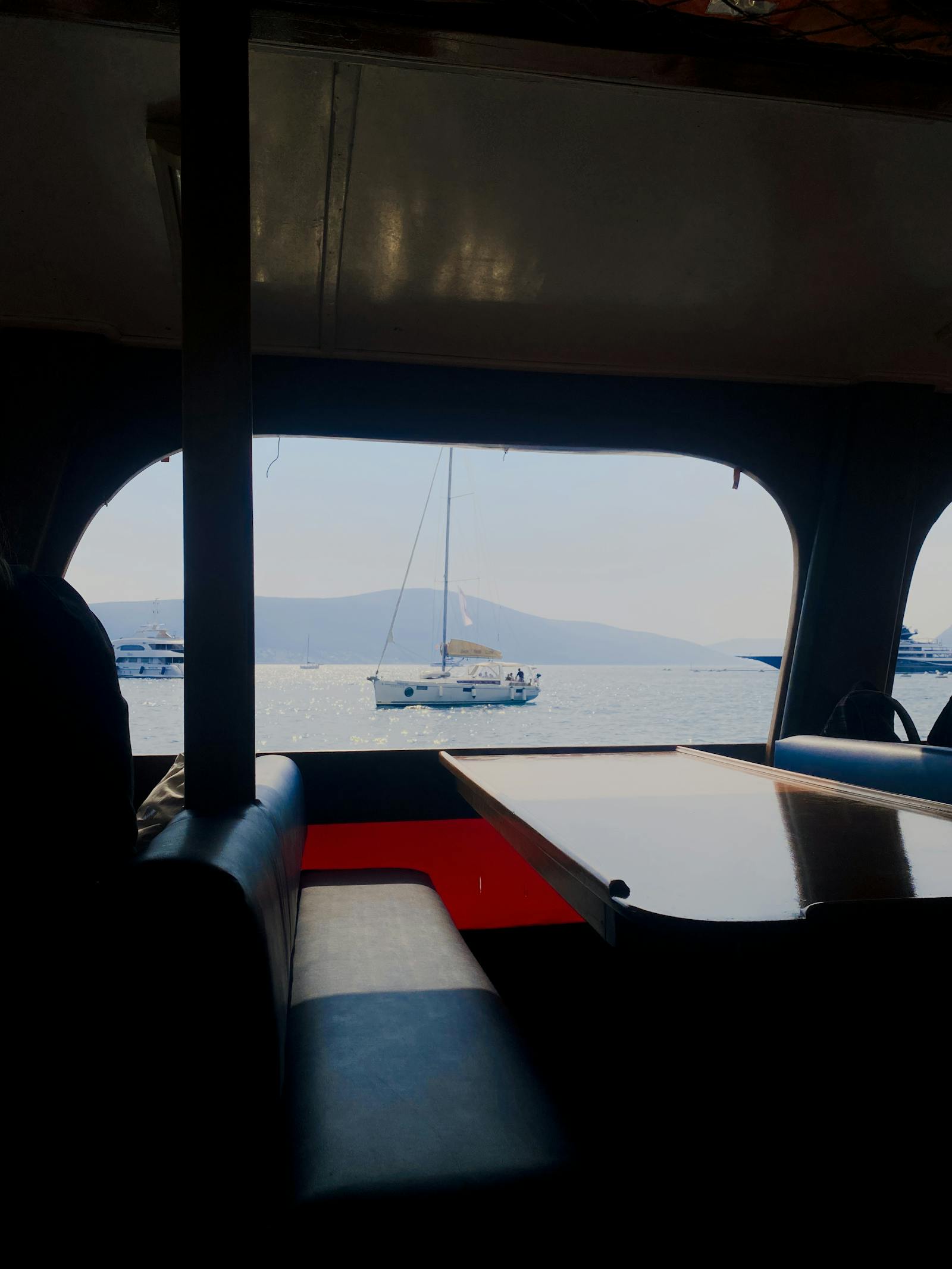 A modern yacht saloon seating area with views of the cockpit and water through the window